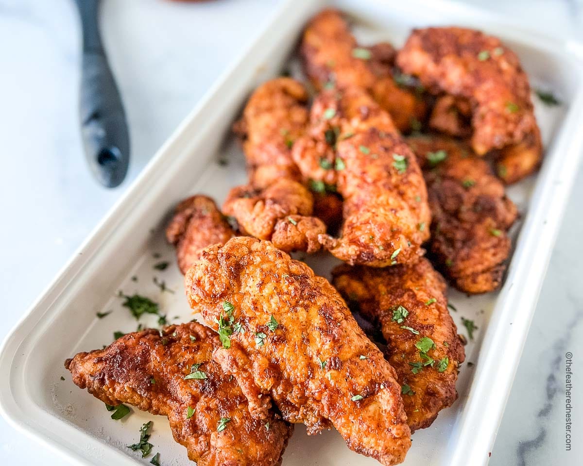 Fried chicken strips on a white serving platter.