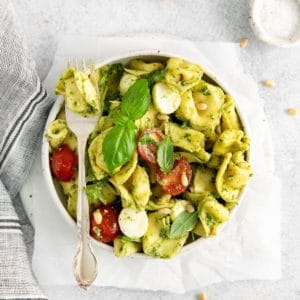 Bowl of cold pesto tortellini salad with a fork placed on top.