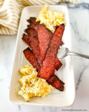 a white platter with turkey bacon and scrambled eggs