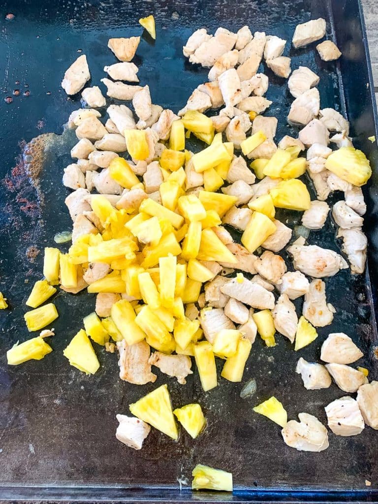 cooking the pineapple chunks and chicken tenders on a Blackstone griddle grill