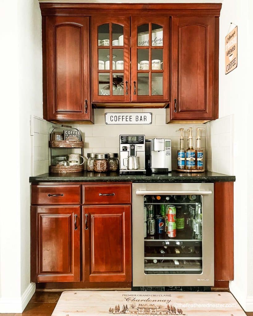 coffee bar with cabinets on top and bottom and a espresso maker, coffee maker, coffee signs, and bottles of coffee syrups