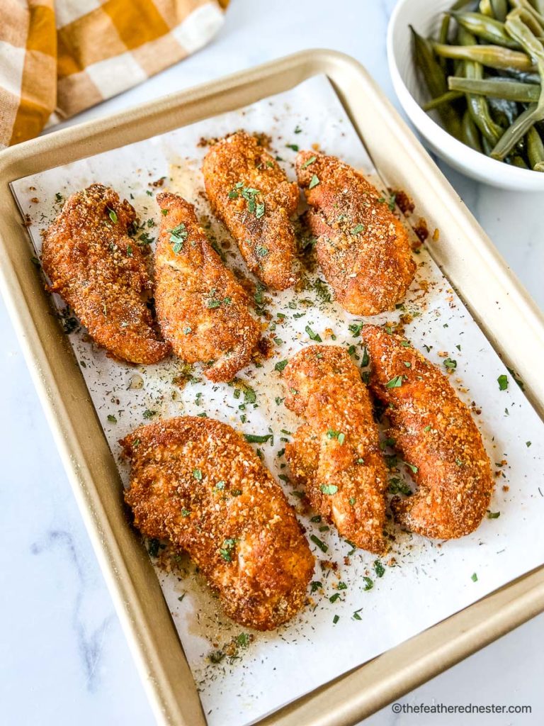 Crispy baked panko chicken tenders on parchment lined baking pan.