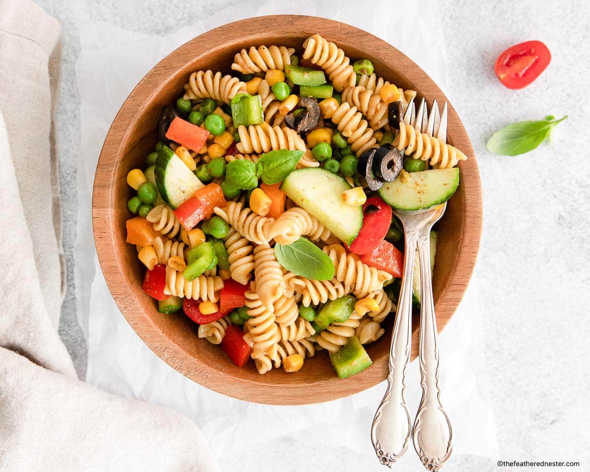 Zesty Italian Pasta Salad and silverwares on a wood bowl.