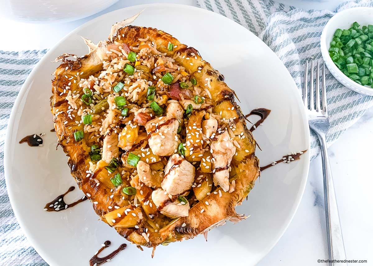 Serving of Hawaiian chicken fried rice in a pineapple bowl glazed with teriyaki sauce.
