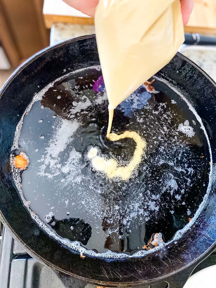 pouring the funnel cake mixture in a hot oil using a Ziplock piping bag.