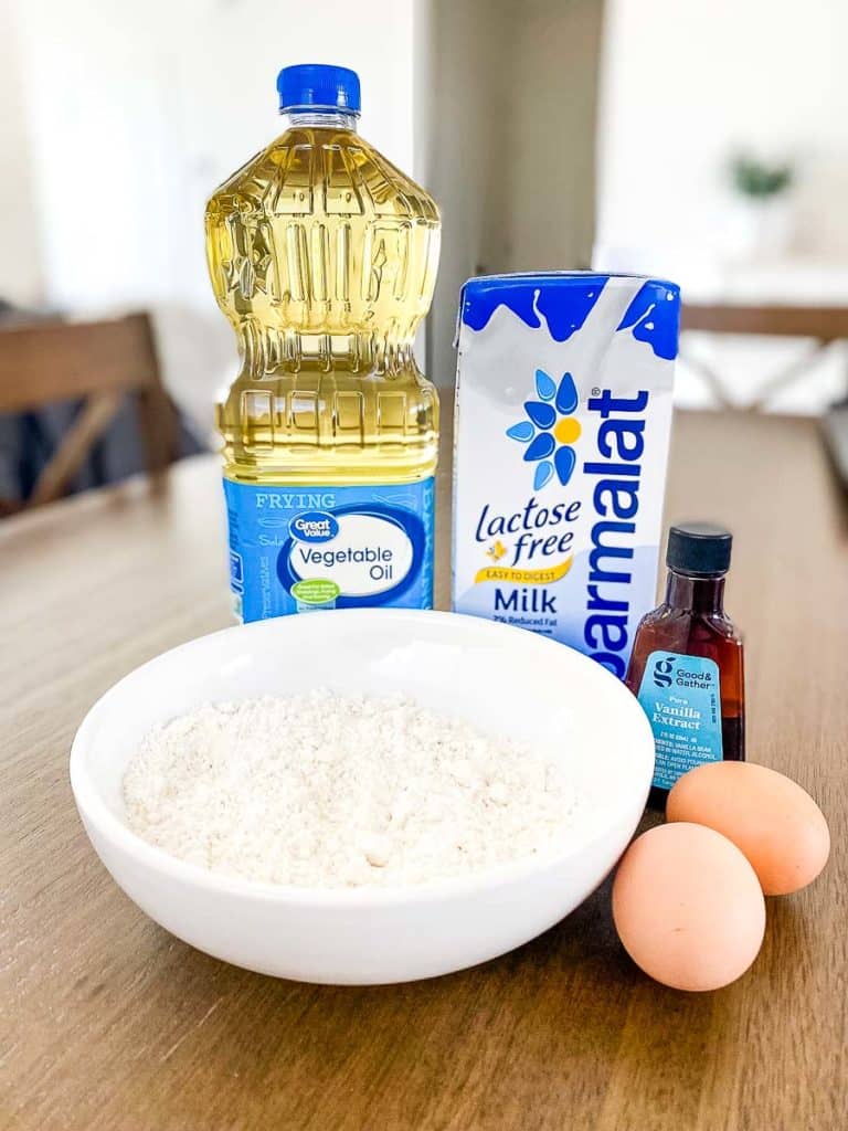 ingredients for making homemade funnel cake which consists of vegetable oil, milk, vanilla extract, eggs, and a Bisquick baking mix.
