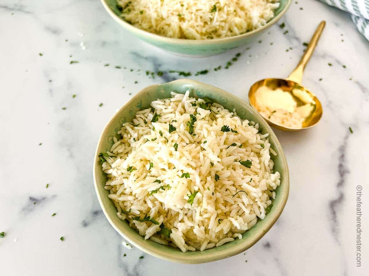 A green bowl with Instant Pot Jasmine rice and a golden serving spoon, and another large bowl of rice at the side.  