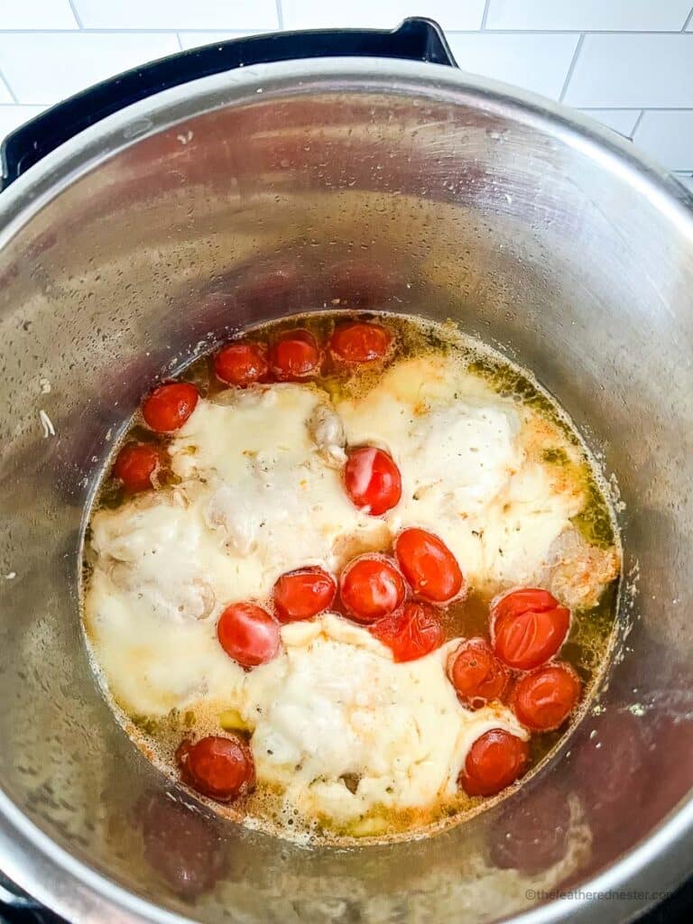 Instant Pot with chicken thighs, cherry tomatoes and broth inside.