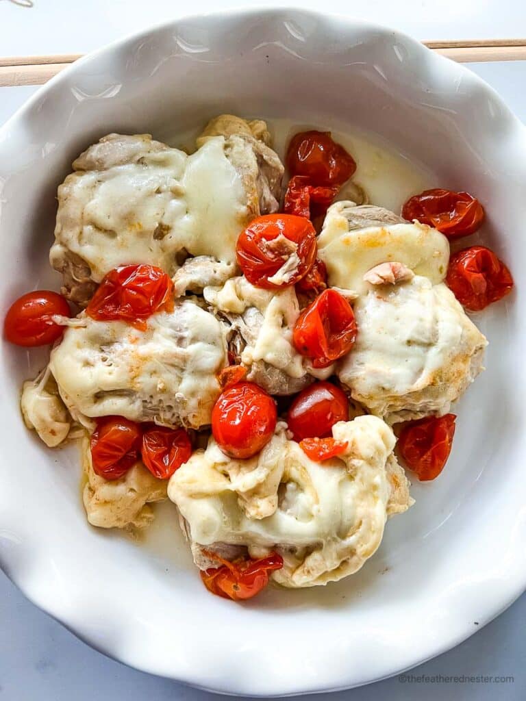 a white plate with chicken, mozzarella, and cherry tomatoes.