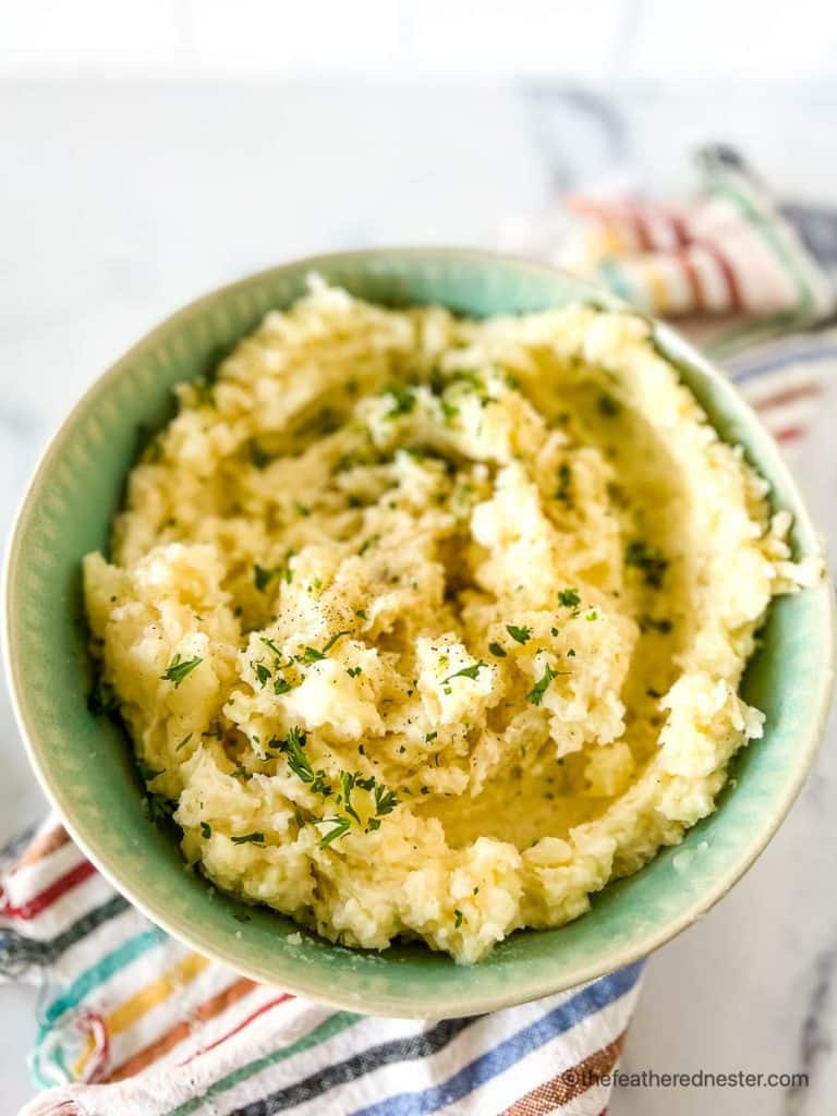 a green bowl full of potatoes ready to serve