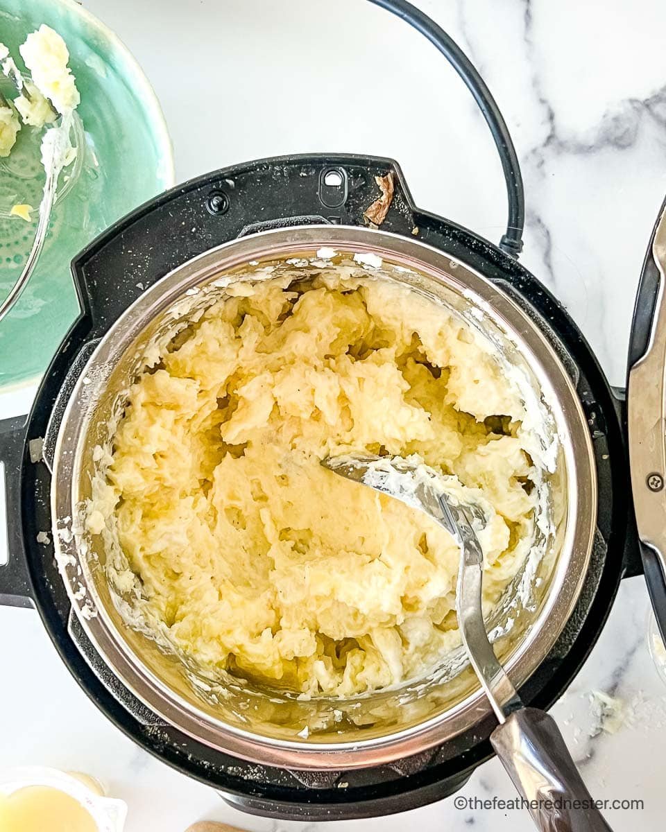 Stirring seasonings into Instant Pot red mashed potatoes.