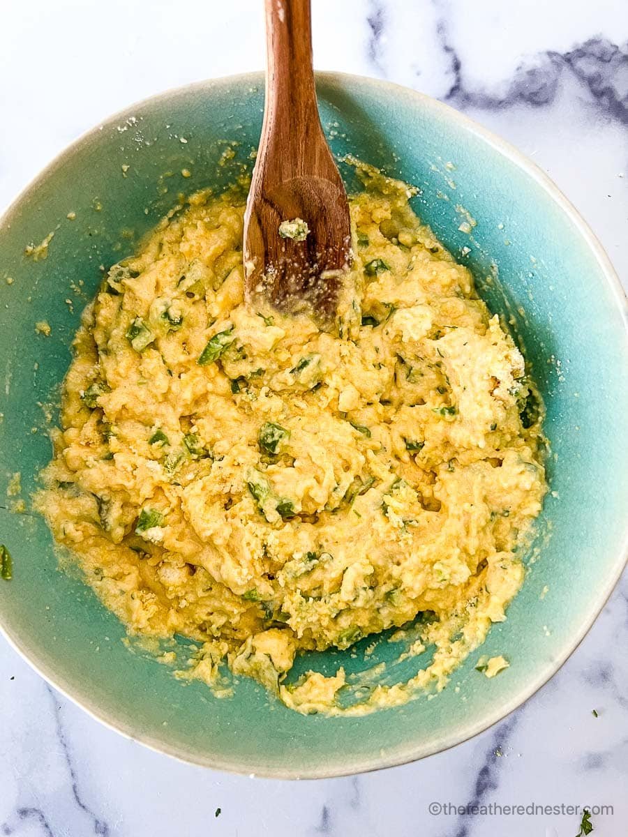 Jiffy jalapeno cornbread ingredients stirred using a wooden spoon inside a medium bowl.