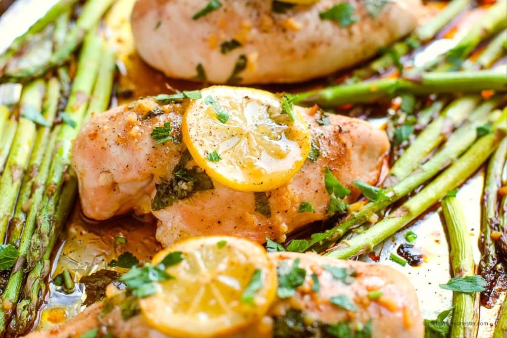 chicken and asparagus bake in one pan with garnish and slice of lemon on top