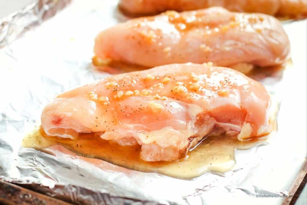 chicken breast with minced garlic and honey lemon sauce in an aluminum foil placed on a baking sheet