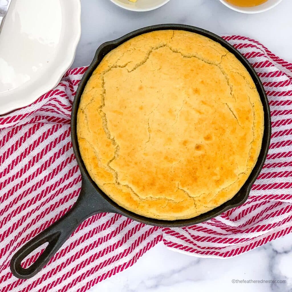 a cast iron skillet with self rising cornbread sitting on a red striped kitchen towel
