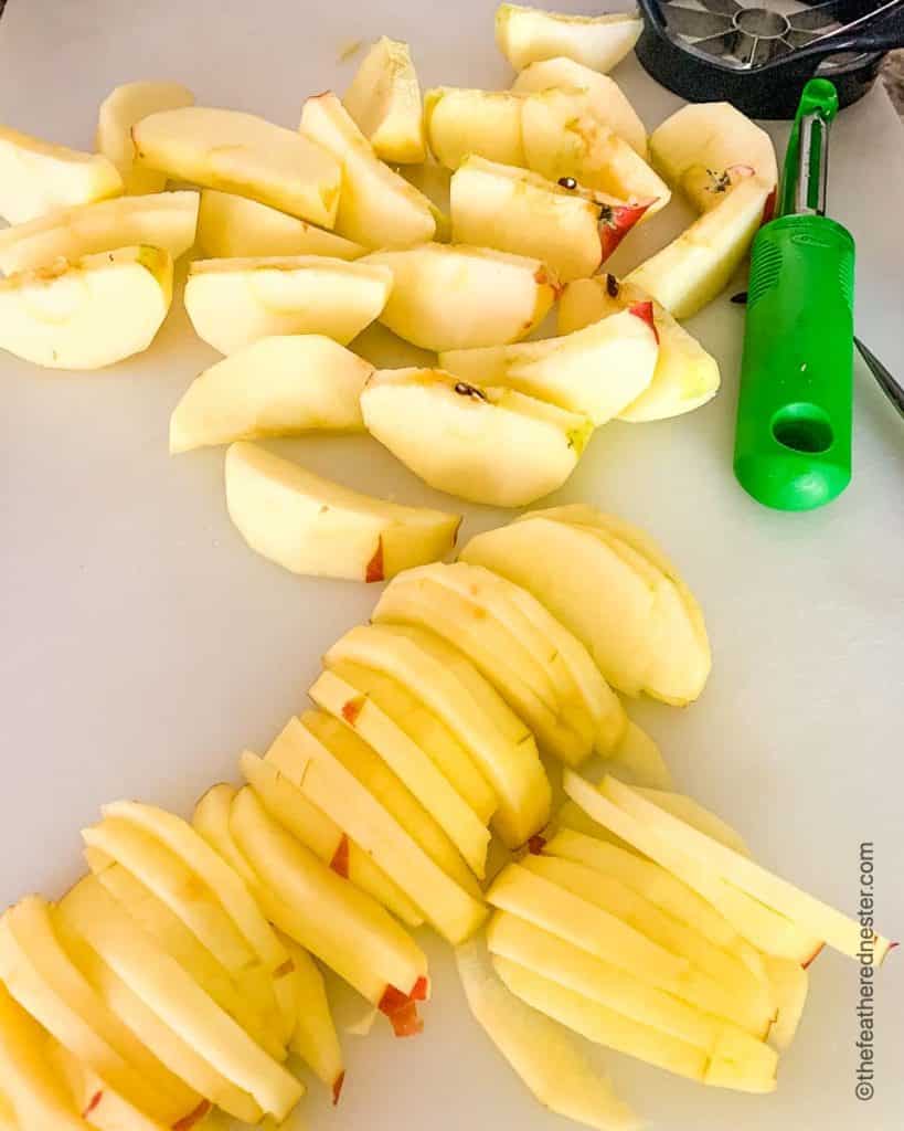 sliced apples with a green peeler and apple corer in the background