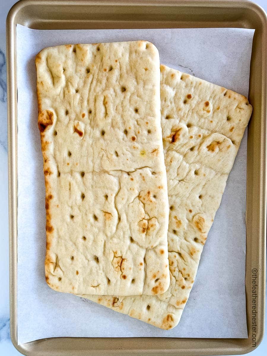 a parchment covered baking sheet with two flatbread pizzas.