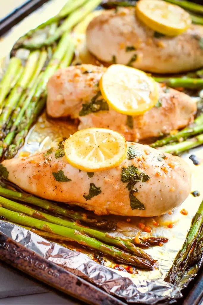 baking chicken with asparagus in one pan with a slice of lemon on top