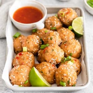 sweet chili meatballs with slices of lime places in a baking sheet.