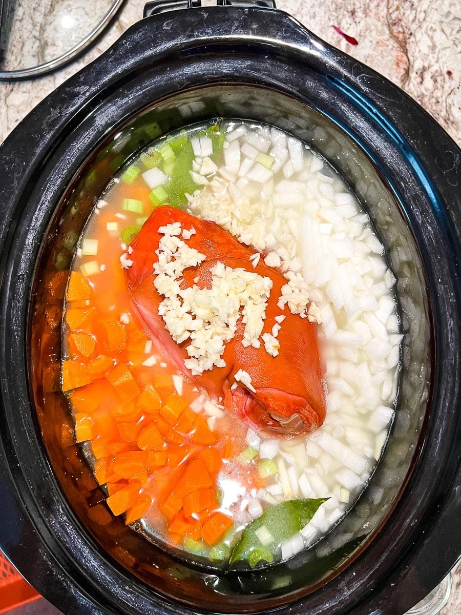 Northern beans in crock pot with vegetables and broth.