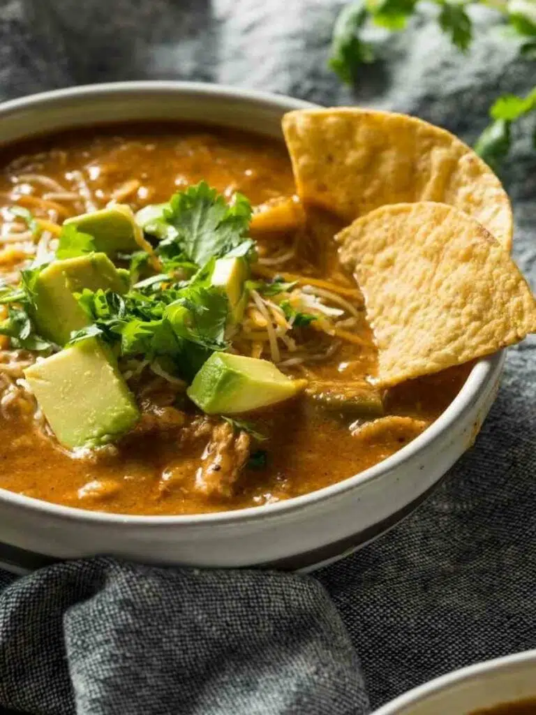 a white bowl with Instant Pot Creamy Chicken Tortilla Soup and two pieces of tortilla chips on top.