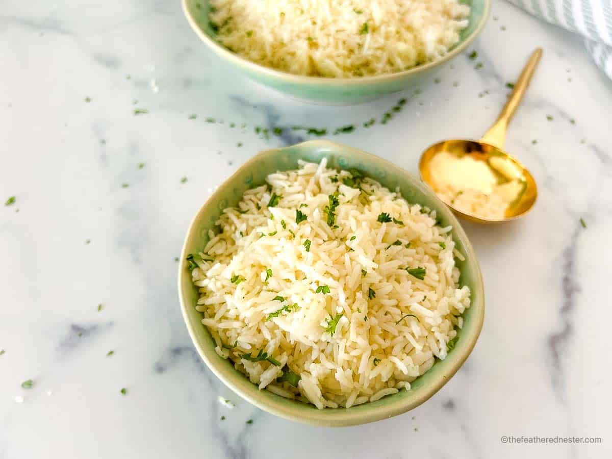Coconut milk rice in a green bowl next to a gold serving spoon.