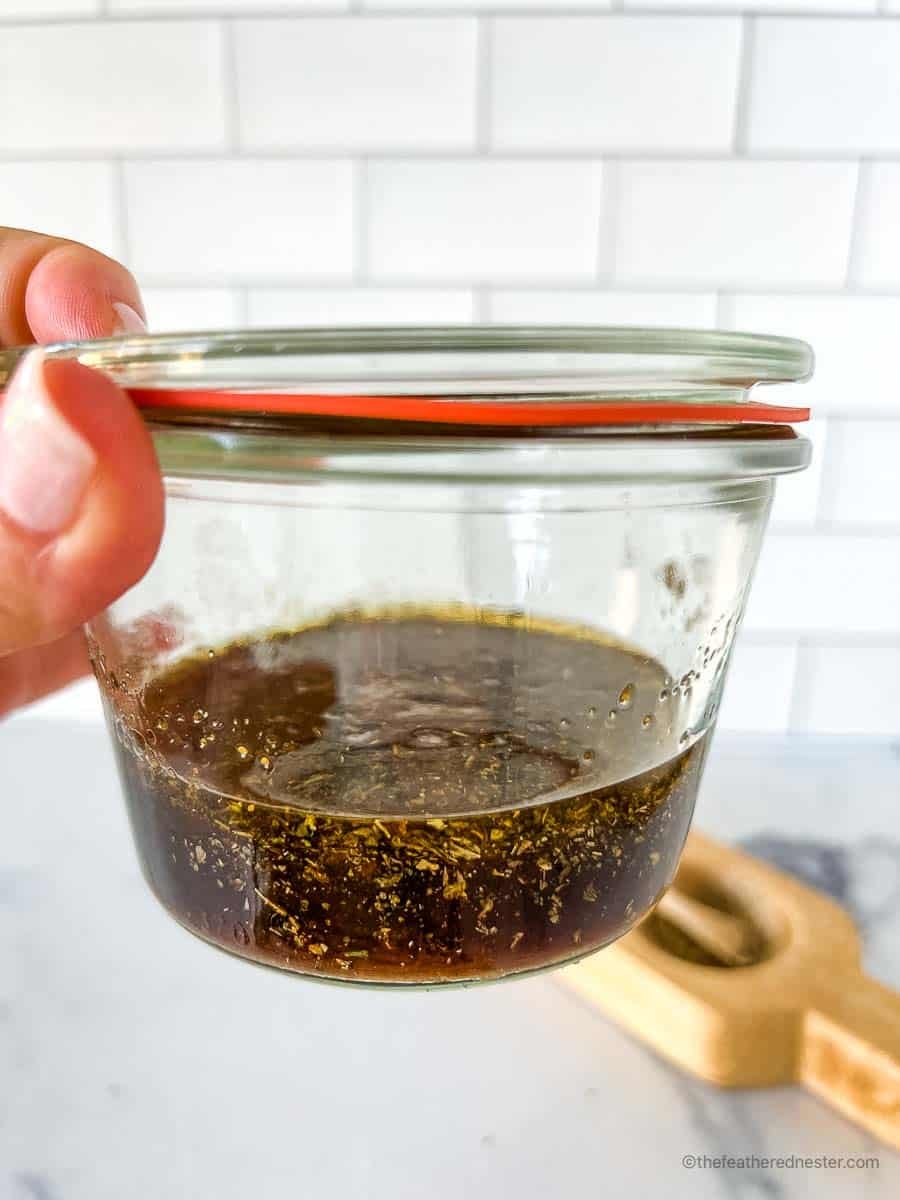 Balsamic marinade for chicken placed in a glass jar with a salt and pepper cellar in the background.