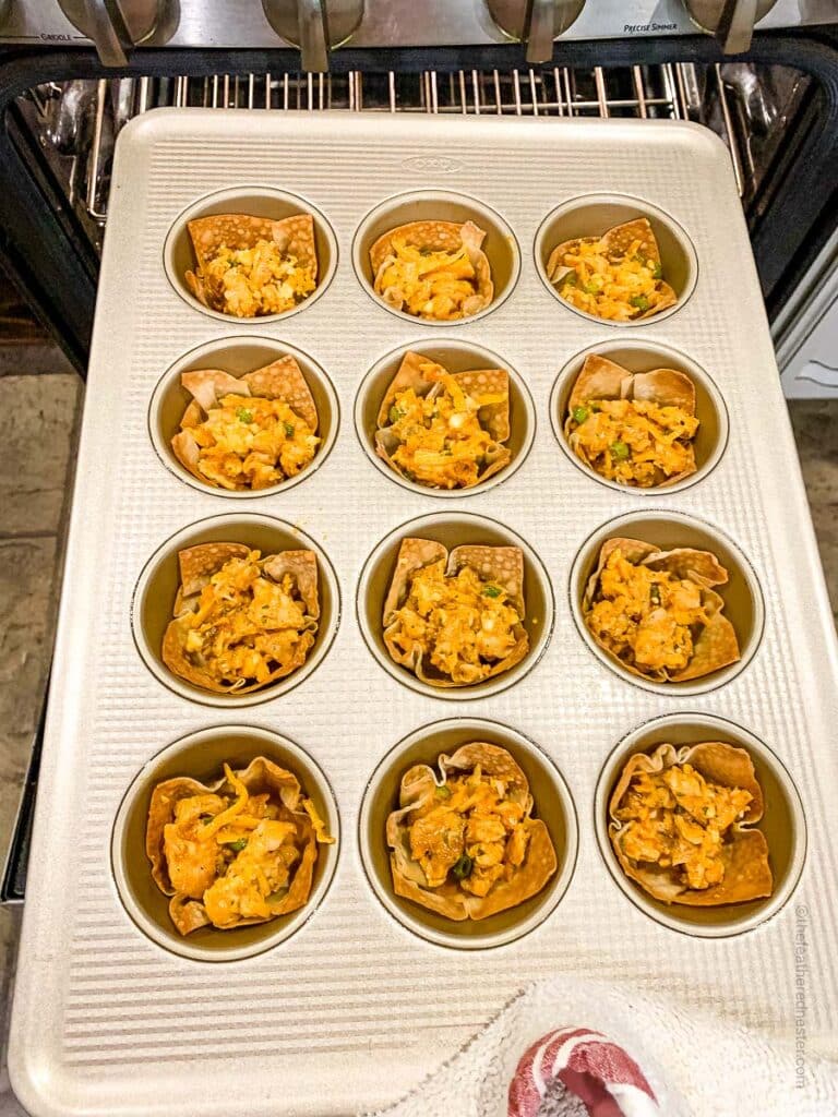 a muffin pan with baked buffalo chicken wonton cups.