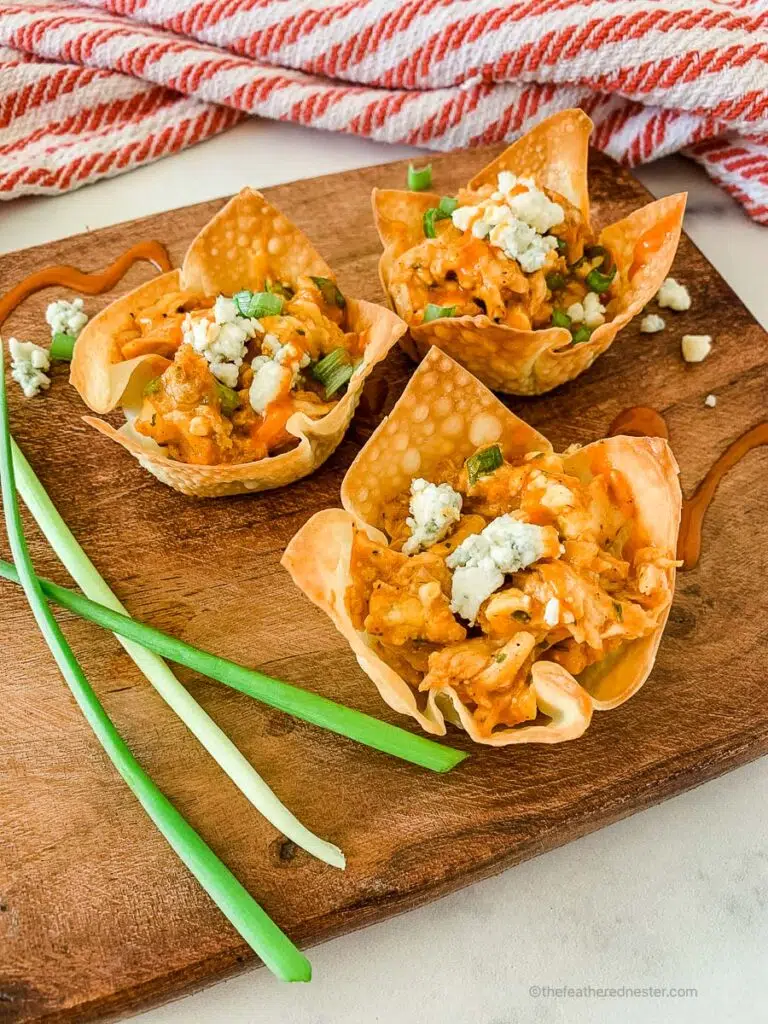 buffalo chicken wonton cups in a wooden serving tray.