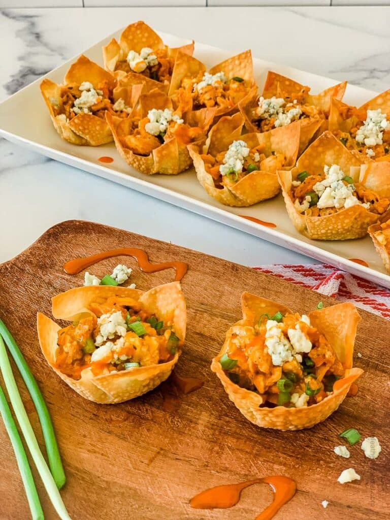 buffalo chicken wonton cups placed in a wooden serving tray and white serving plate.
