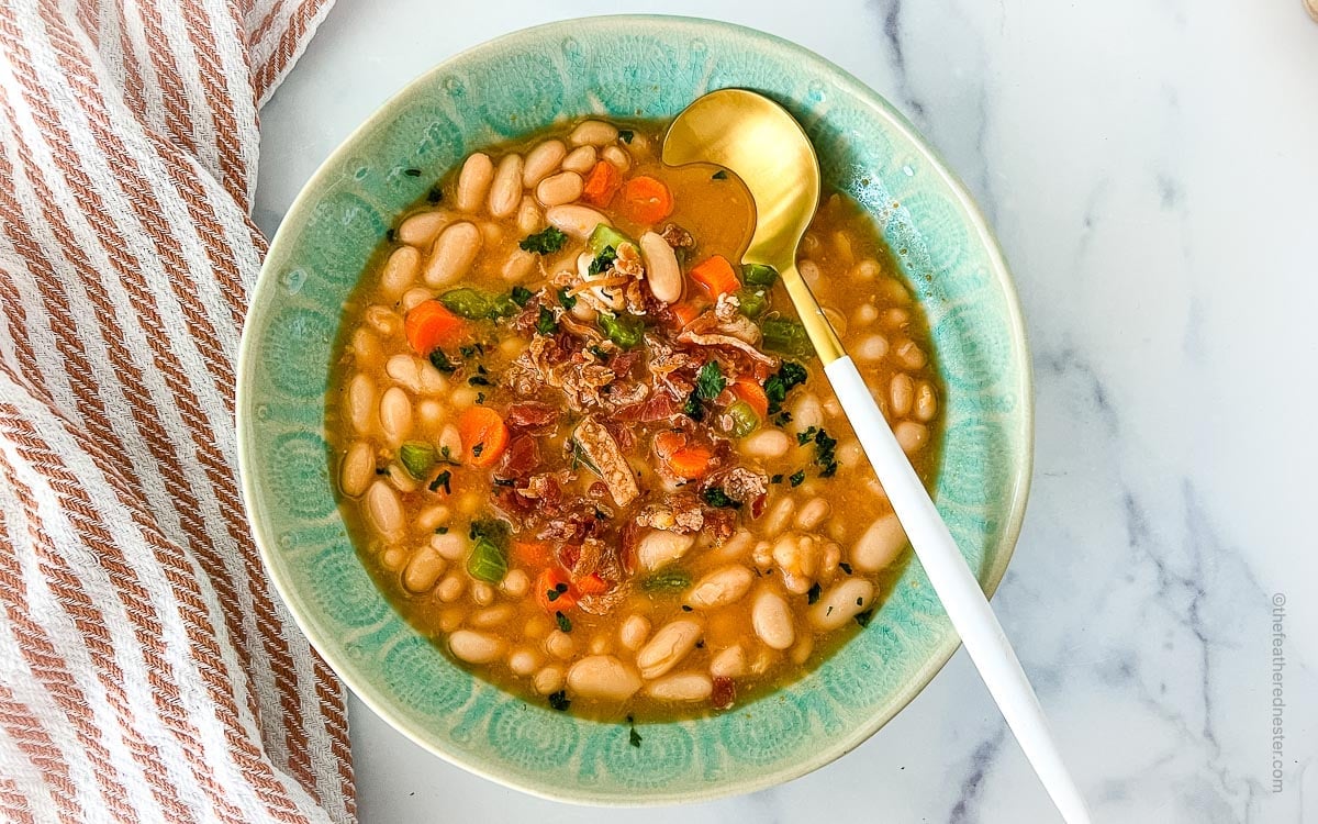 A bowl of great northern beans soup with a gold spoon