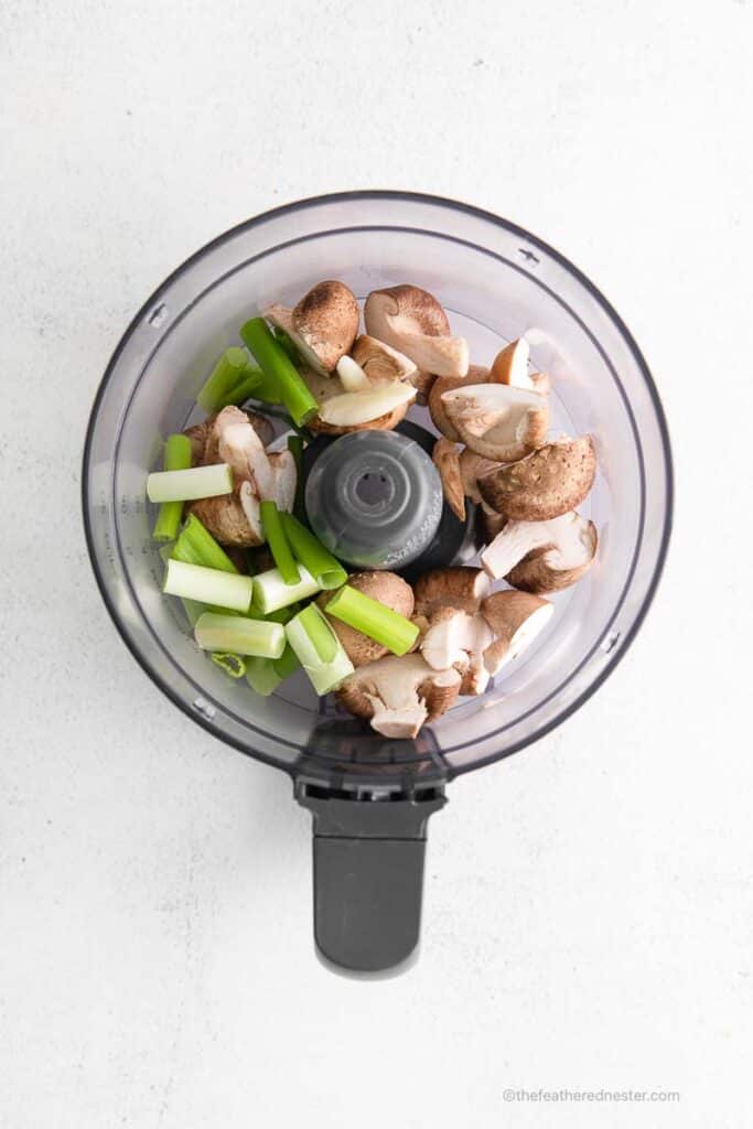 mushrooms, garlic, and green onions are placed inside the food processor.
