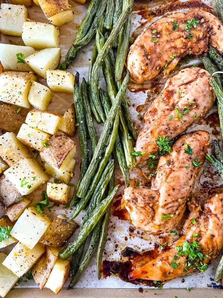baked chicken tenders with baked potatoes and asparagus beside it.
