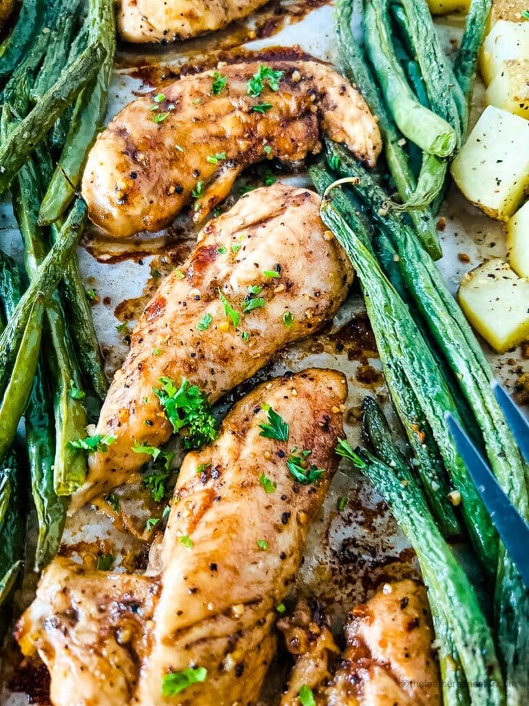 oven baked chicken tenders with asparagus and potatoes beside it.