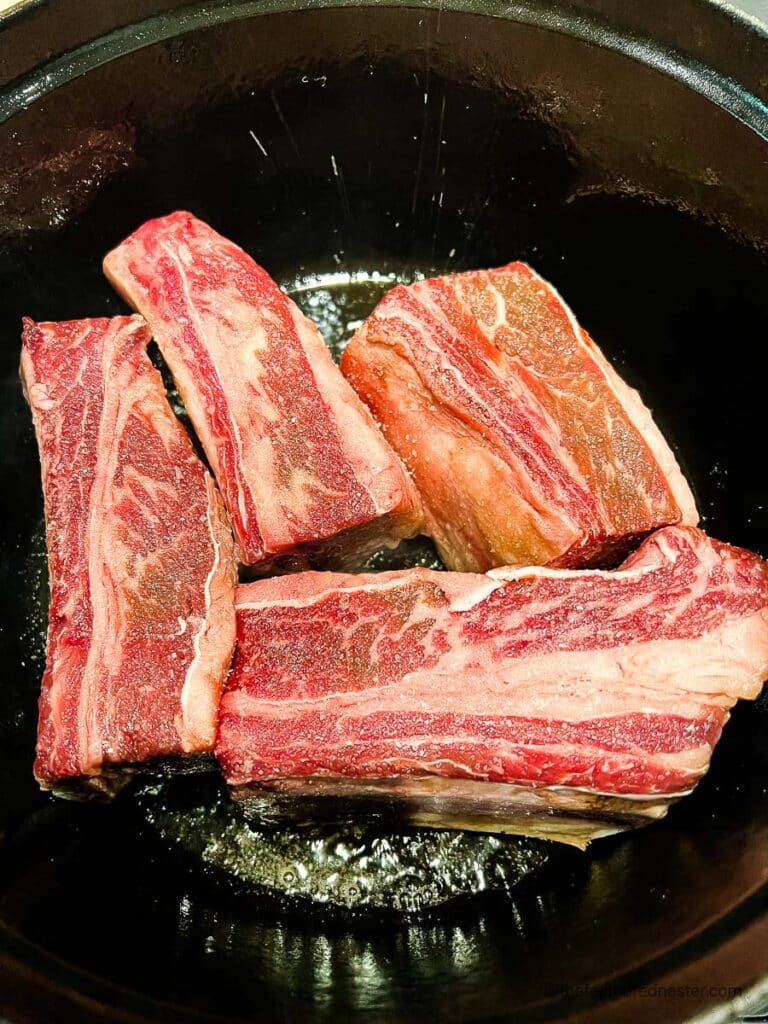 beef short ribs placed in a Dutch oven.