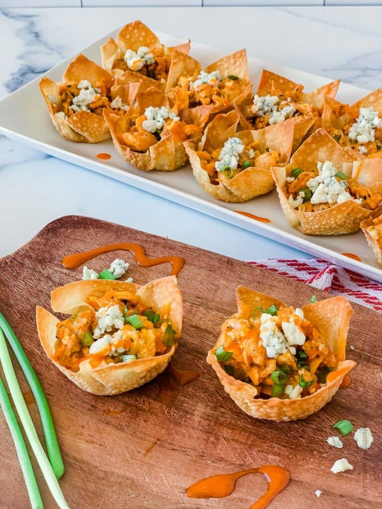 buffalo chicken appetizers placed on a wooden serving tray and white serving platter.