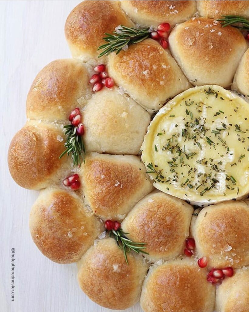 Festive holiday baked camembert appetizer, garnished with pomegranate arils and fresh herbs.