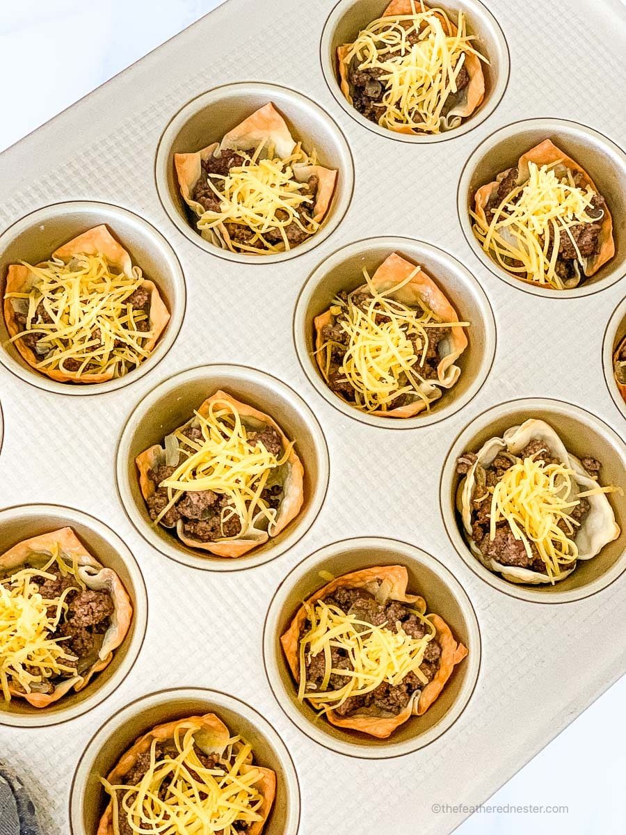 muffin tin with wontons, ground beef, and shredded cheese