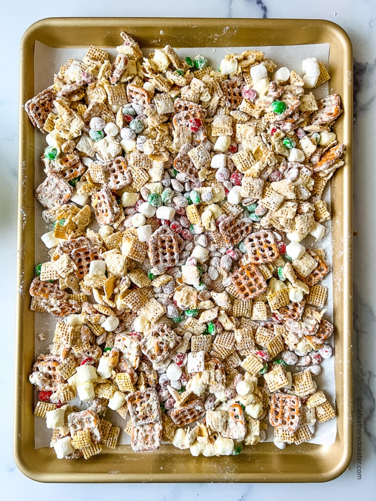 a baking sheet full of Christmas Chex Mix drizzled with white chocolate.