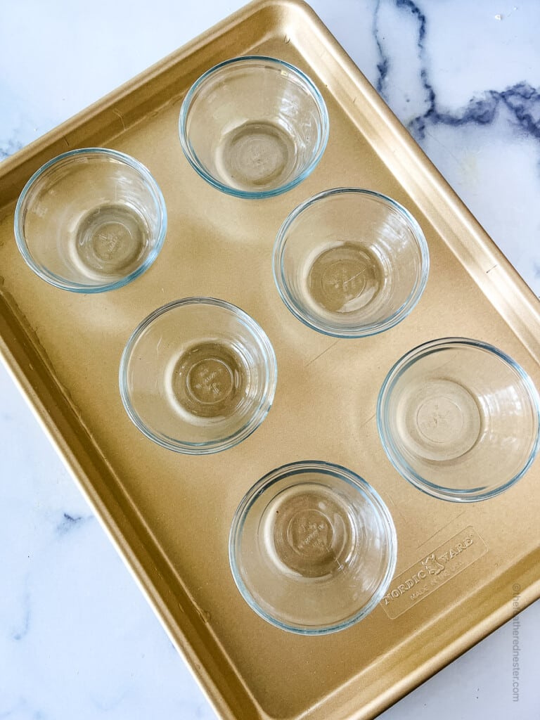 Small clear glass ramekins on a baking sheet.