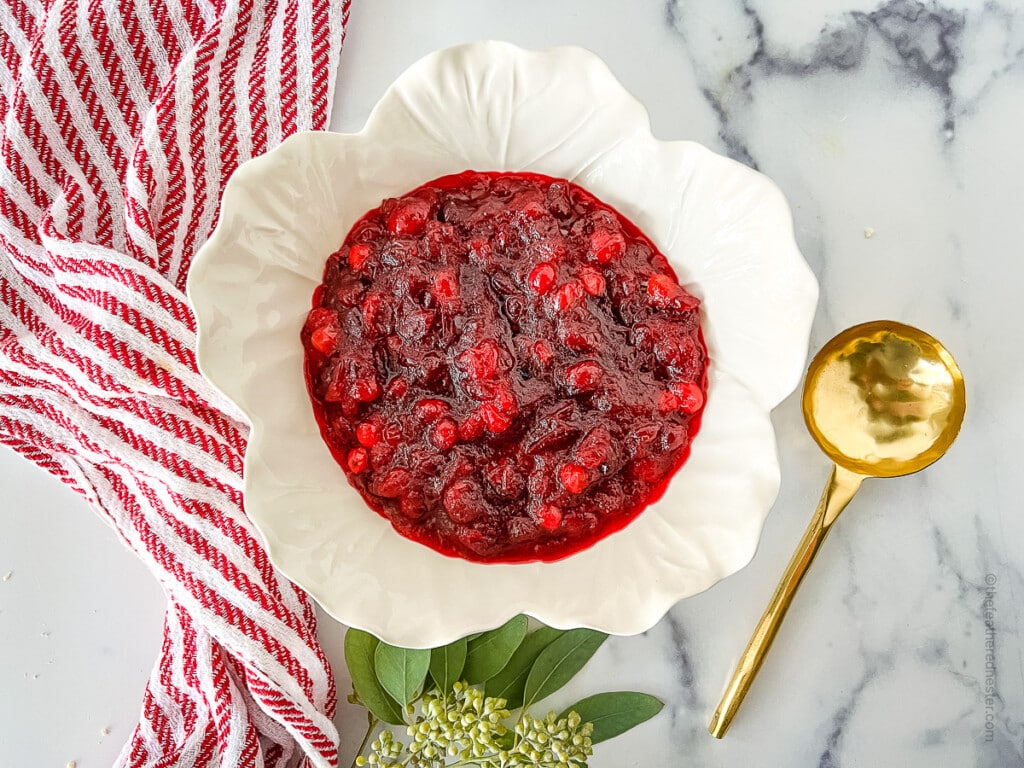 a white bowl of cooled and thickened cranberry sauce with orange juice.