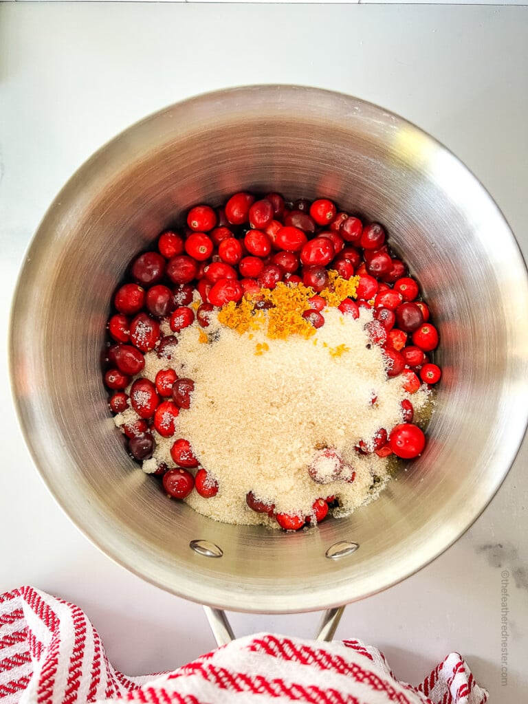 a sauce pan with cranberries, orange juice, sugar, and orange zest