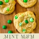 green m and m cookies on a wooden serving board with writings on the bottom