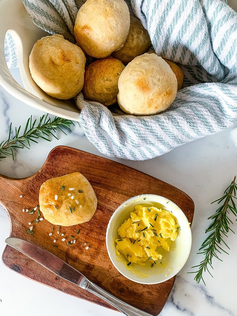 Sourdough rolls on a basket and a wooden board.