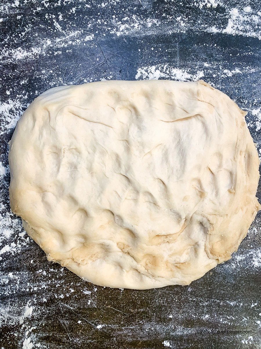 Sourdough rolls dough mixture on a floured countertop.