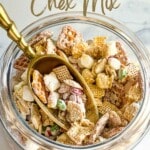 A jar of Christmas Chex Mix with golden scoop. with writings on top and bottom