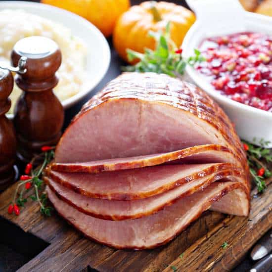 Sliced Crock Pot Dr. Pepper Ham on a wooden board.