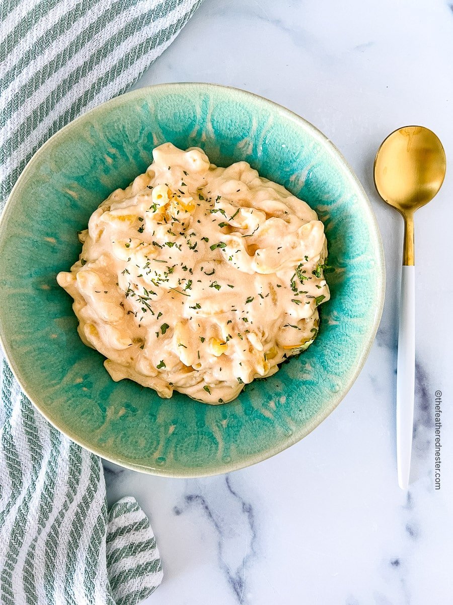 Serving of cheesy pasta in a green bowl.