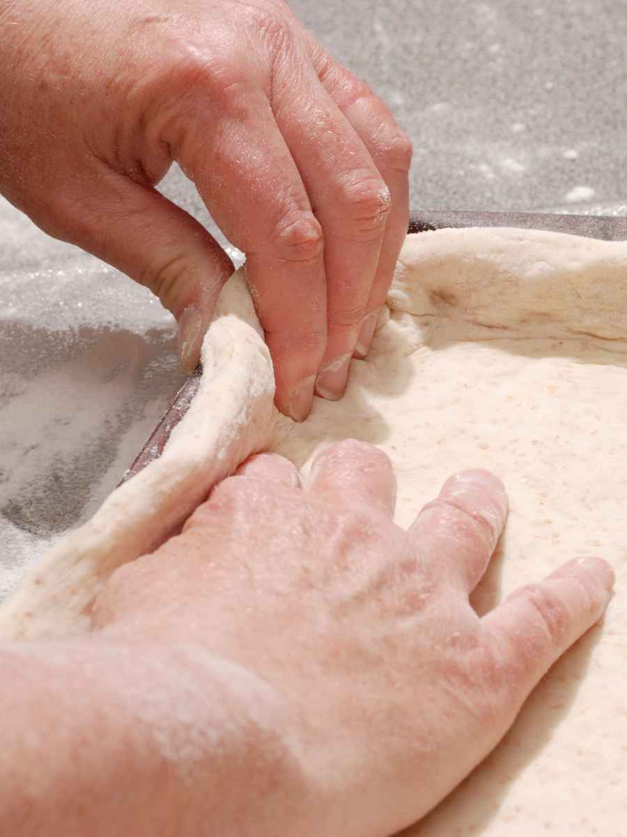 Stretching pizza dough on floured surface.