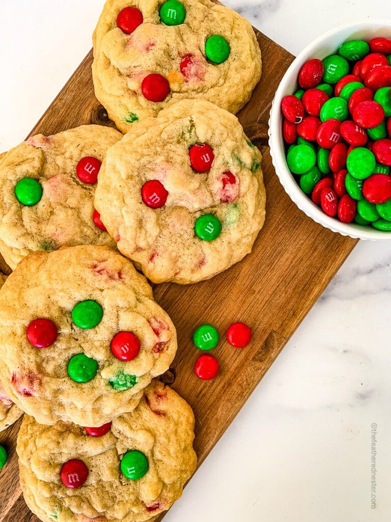 Christmas M&M Cookies on a wooden board and a small bowl with M&Ms on it.